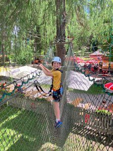 A child smiling on a thrilling high ropes course at Wichtelpark, Sillian, surrounded by trees and outdoor fun. A top pick for adventurous families among the 15 best things to do with kids in Lienz.