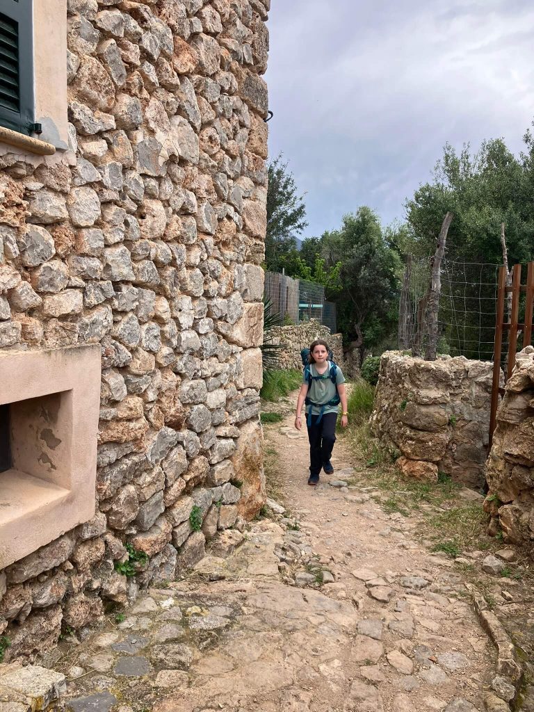 A child walks through a charming stone village path on the GR221 trail between Deià and Sóller—one of the scenic highlights on the GR221 Mallorca hiking itinerary for beginners or families.