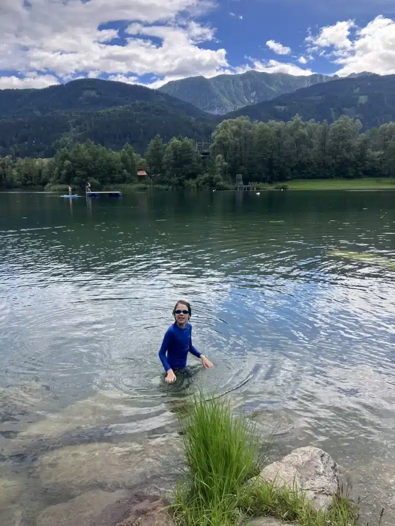 A child stands confidently in a cold mountain lake, illustrating how family travel helps raise resilient children through outdoor challenges and exploration.