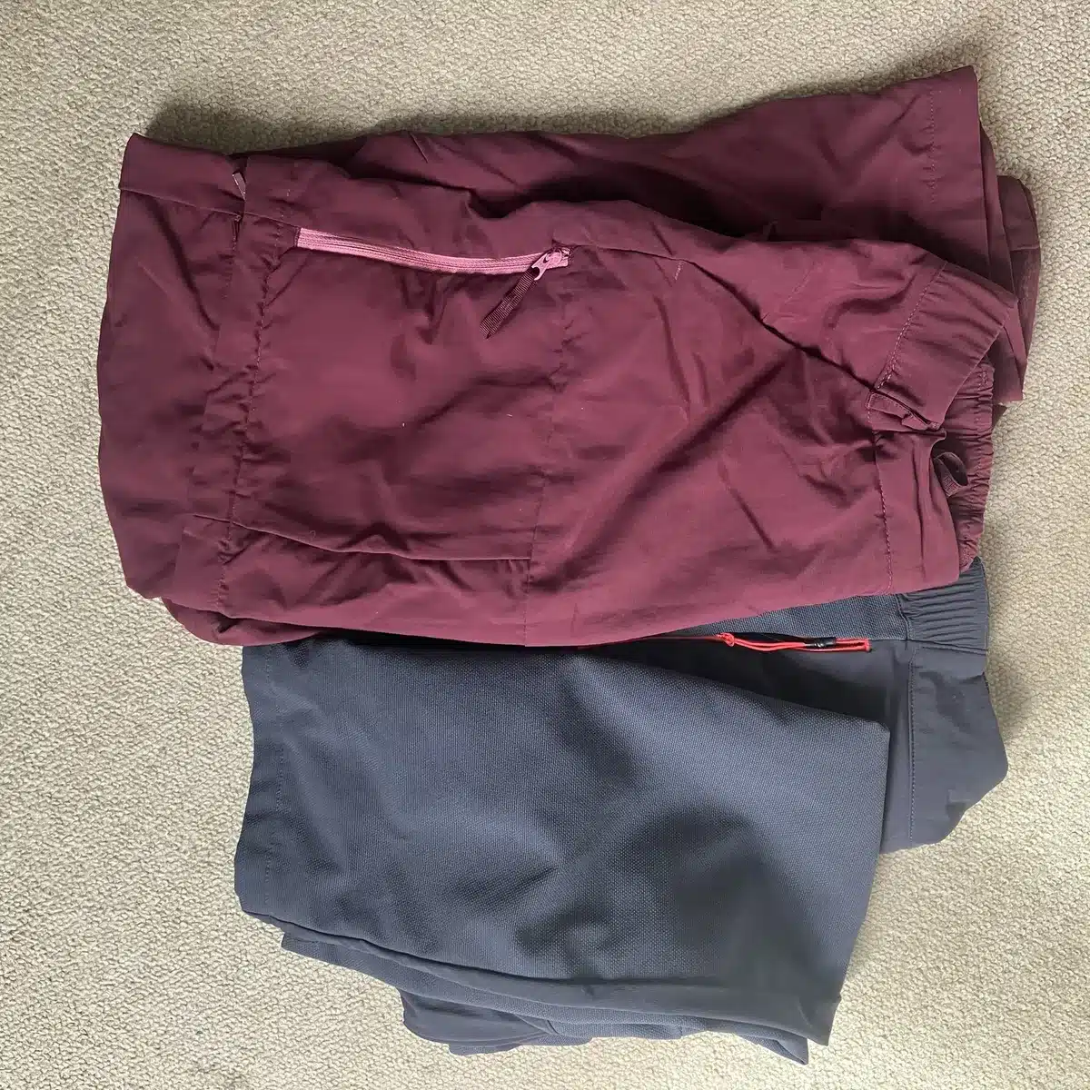 Folded hiking pants in burgundy and black, lightweight and quick-dry fabric for versatile mountain adventures.