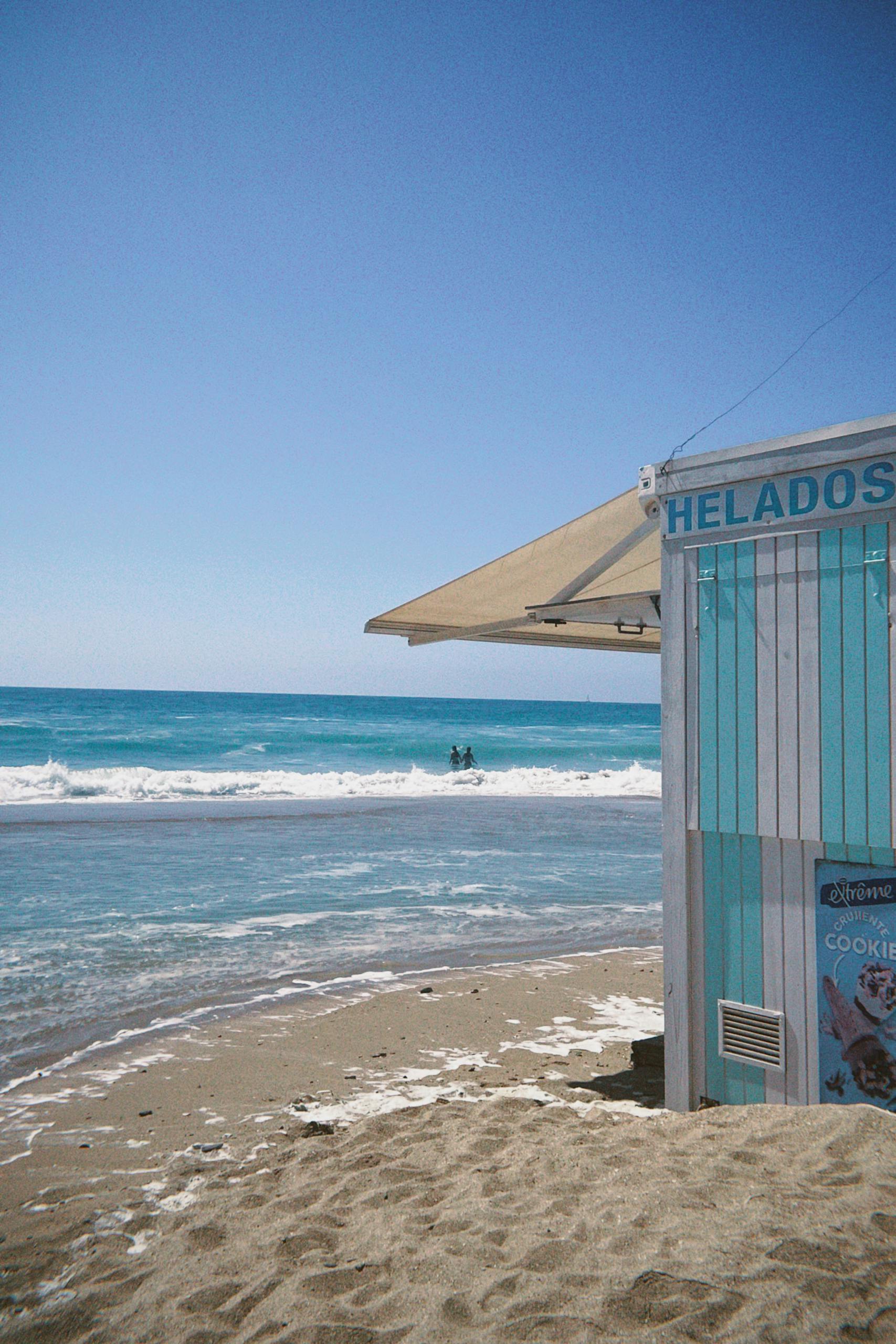Idyllic beach scene with ice cream stand and turquoise waters at Conil de la Frontera, Spain.