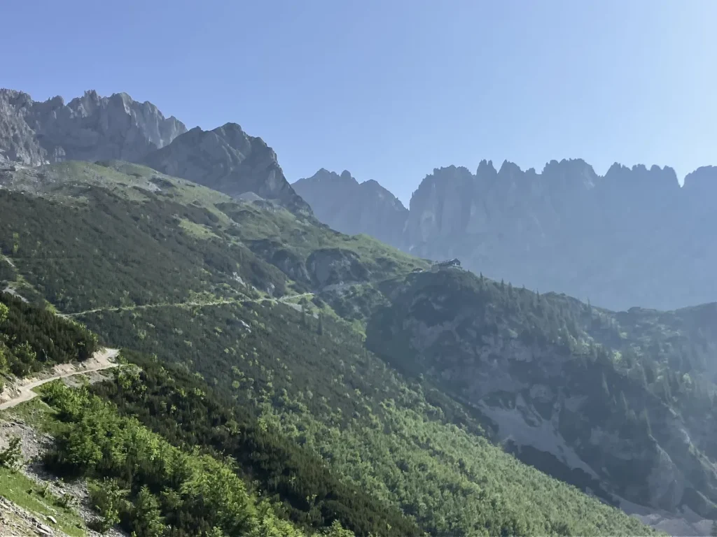 Rugged peaks of the Wilder Kaiser mountains rise sharply above lush green valleys, capturing the dramatic alpine scenery encountered on the hut to hut hike from Kufstein.